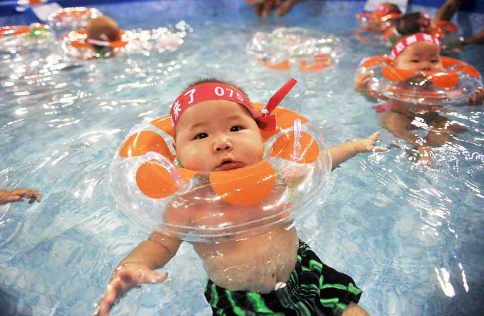 一个中国婴儿在水中抱着一个浮标。