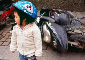 一个中国小女孩站在一辆破摩托车前